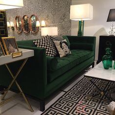 a green couch sitting in a living room next to a table with two lamps on it