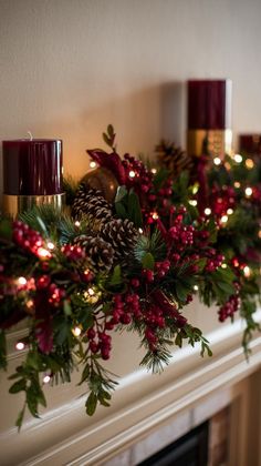 christmas garland with pine cones and red berries on fireplace mantel by lite candles