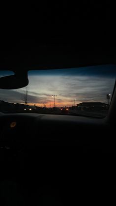 the sun is setting in the distance as seen from inside a car