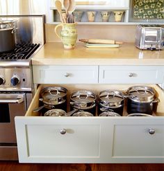 an open drawer in a kitchen with pots and pans sitting on it's side