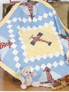 a teddy bear is sitting next to a quilt on a suitcase with an american flag design