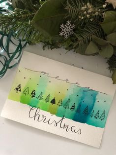 a christmas card with watercolor trees on it