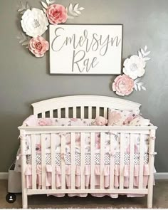 a white crib with flowers on the wall and a sign above it that says, merry