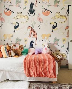 a child's bedroom decorated with colorful wallpaper and stuffed animals on the bed