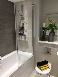 a white toilet sitting in a bathroom next to a bath tub and shower head mounted on the wall