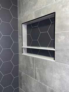 a bathroom with grey tile and hexagonal pattern on the wall, along with a toilet