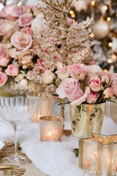 a table topped with vases filled with pink flowers and candles next to a christmas tree