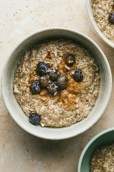 three bowls filled with oatmeal and blueberries on top of a table