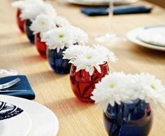 several vases with white flowers are lined up on a table