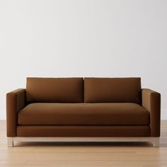 a brown couch sitting on top of a hard wood floor next to a white wall