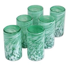 six green glass tumblers sitting next to each other on a white surface with swirl designs