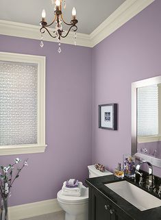 a bathroom painted in purple and white with a chandelier hanging from the ceiling