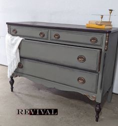 an old dresser is painted gray with gold hardware