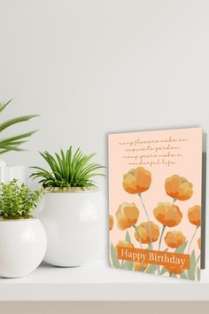 there is a happy birthday card on the shelf next to two potted plants and a plant