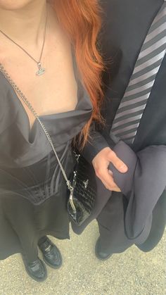 a woman with long red hair wearing a black dress and holding onto a man's tie