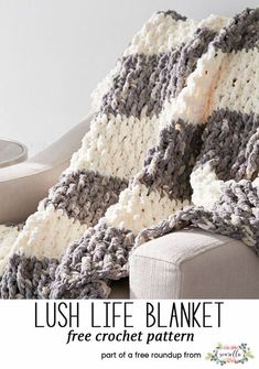 a crocheted blanket sitting on top of a couch next to a white chair