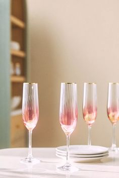 four wine glasses sitting on top of a white table