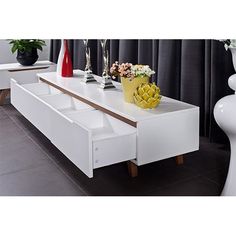 a white coffee table with drawers and vases