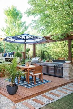 an outdoor kitchen and dining area is shown in this backyard setting with wood decking