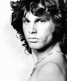 a black and white photo of a young man with curly hair wearing a tank top