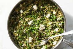 a pot filled with pasta and peas on top of a white counter next to a fork