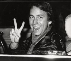 a man sitting in a car making the peace sign