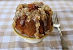 a close up of a cake in a bowl on a table with a knife and fork