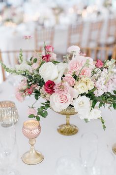 a vase filled with lots of pink and white flowers sitting on top of a table