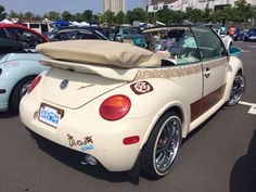 the back end of a convertible car parked in a parking lot next to other cars