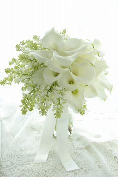 a bouquet of white flowers sitting on top of a lace covered table cloth next to a window