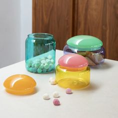 three jars filled with candy sitting on top of a table next to other containers and candies