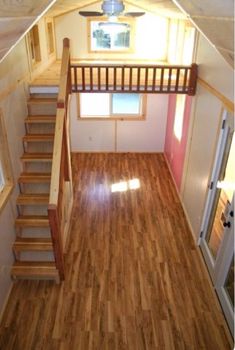 the inside of a tiny house with wood floors and stairs leading up to an upstairs loft