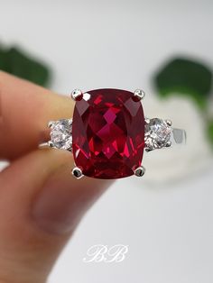 Made to order.  Please allow up to 3 weeks for the production of your selection. This listing is for a 925 non-plated sterling silver or non-plated gold three stone trellis ring with a high quality lab created ruby elongated cushion cut gemstone and high quality cubic zirconia diamond accent stones. Center Stone Gem Type: Lab Created Ruby Shape: Elongated Cushion Cut Size: 10x8mm Weight: 3.5 carats approximately Quality: AAA Hardness: 9 Mohs Accent Stones Gem Type: Lab Created Cubic Zirconia Diamonds Shape: Round Brilliant Size: (2) 3.5mm Color: White Quality: 6A Hardness: 8.5 Mohs Available in the following Metal Options (all metal are non-plated and solid) 925 Sterling Silver 10kt White Gold (non-rhodium plated) 10kt Yellow Gold 14kt White Gold (non-rhodium plated) 14kt Yellow Gold 14kt Classic Lab-created Ruby Jewelry For Promise, Classic Promise Jewelry With Lab-created Ruby, Elegant Cushion Cut Lab-created Ruby Jewelry, Elegant Lab-created Ruby Jewelry For Promise, Elegant Jewelry With Lab-created Ruby For Promise, Classic Cushion Cut Ruby Jewelry, Rectangular Stone Ring Hallmarked For Anniversary, Hallmarked Rings With Rectangular Stone For Anniversary, Rectangular Stone Hallmarked Rings For Anniversary