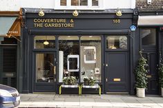 a store front with plants in the window and cars parked on the street outside it