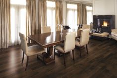 a dining room table with chairs and a fire place in the corner behind it on a hard wood floor