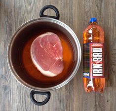 a pot filled with liquid next to a piece of meat on top of a wooden table