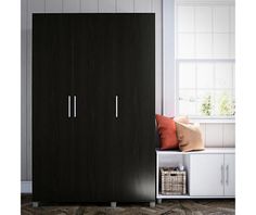 a black wardrobe with two doors next to a window and some pillows on the floor