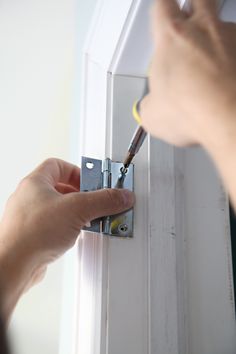 a person is fixing a door handle on a white door with screwdrivers in their hands