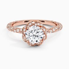 an engagement ring with a flower design on the band and round brilliant cut diamond in the center