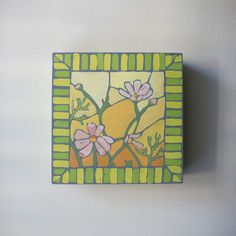 a small square painting with flowers painted on it