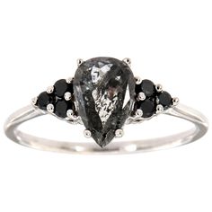 a white gold ring with black diamonds on the sides and an oval cut diamond in the middle