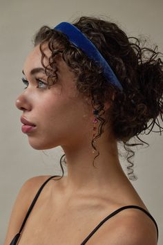 a woman with curly hair wearing a blue headband and looking off to the side