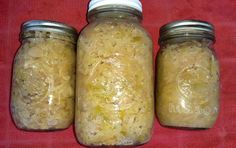 three jars filled with food sitting on top of a red table cloth next to each other