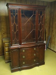 an old wooden china cabinet sitting in a room with wood paneling on the walls