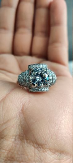 a close up of a person's hand holding an engagement ring