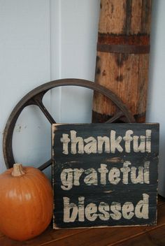 a wooden sign sitting on top of a table next to a pumpkin