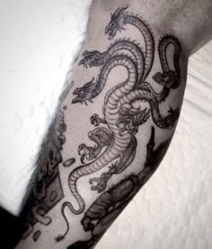 a black and white photo of a dragon tattoo on someone's left arm,