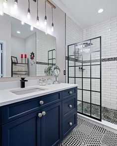 a bathroom with black and white checkered flooring, blue cabinets and a shower stall