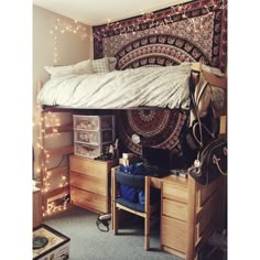 a dorm room with a bed, desk and hanging tapestry on the wall above it