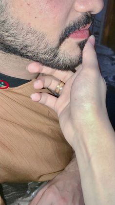 a close up of a person with a ring on his finger and wearing a t - shirt